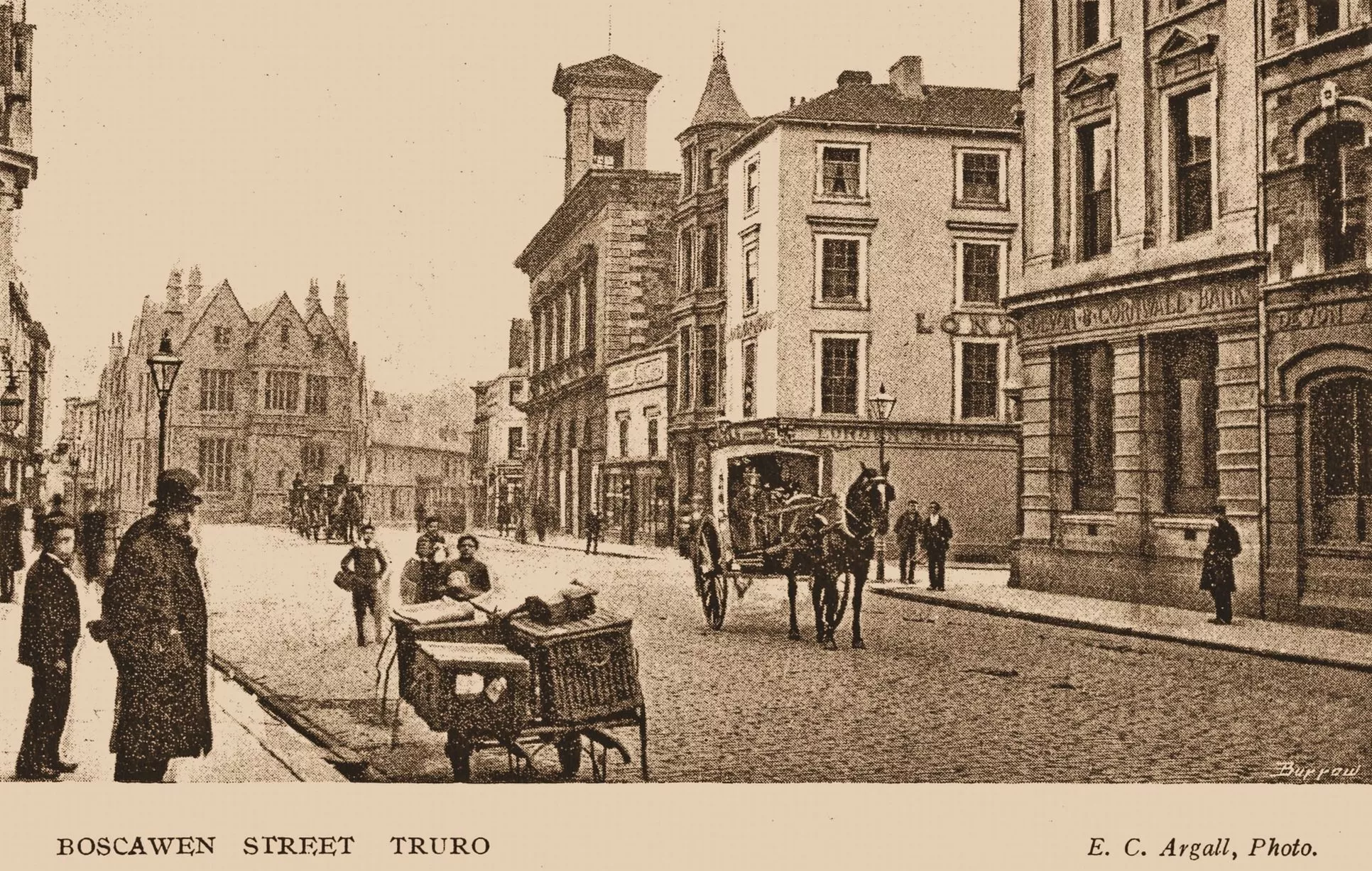 Christine Parnell and Sheila Richardson write: "This pre-First World War photo clearly depicts the transport of the era. On the site of the present Lloyds Bank is the Devon and Cornwall Bank. Opposite is London House, which is clearly marked showing the many windows. Over the years this building has had various alterations but presently the windows are covered up. In the foreground of the picture are wicker hampers on a hand cart, which were used for deliveries."